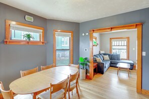 Ein Wohnzimmer mit einem Holzesstisch, Stühlen, einer Couch und einer Topfpflanze.