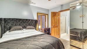 Ein Schlafzimmer mit einem großen Bett, einem Holzschrank und einer Glastür zu einem anderen Raum.