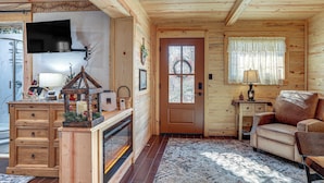 A cozy cabin interior with a wooden interior, a fireplace, a television, and a comfortable seating area. - Walk to Current River: Ozarks Adventure Home! (Van Buren)