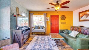 A living room with a sofa, a coffee table, a TV, and a ceiling fan. - Fire Pits & Grill at Central Tucson Home Base! (Tucson)