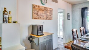 A dining area with a wooden table, chairs, a clock, and a world map artwork on the wall. - Fire Pits & Grill at Central Tucson Home Base! (Tucson)
