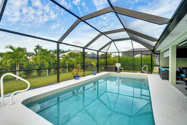 Piscina techada con vista a palmeras y casas.