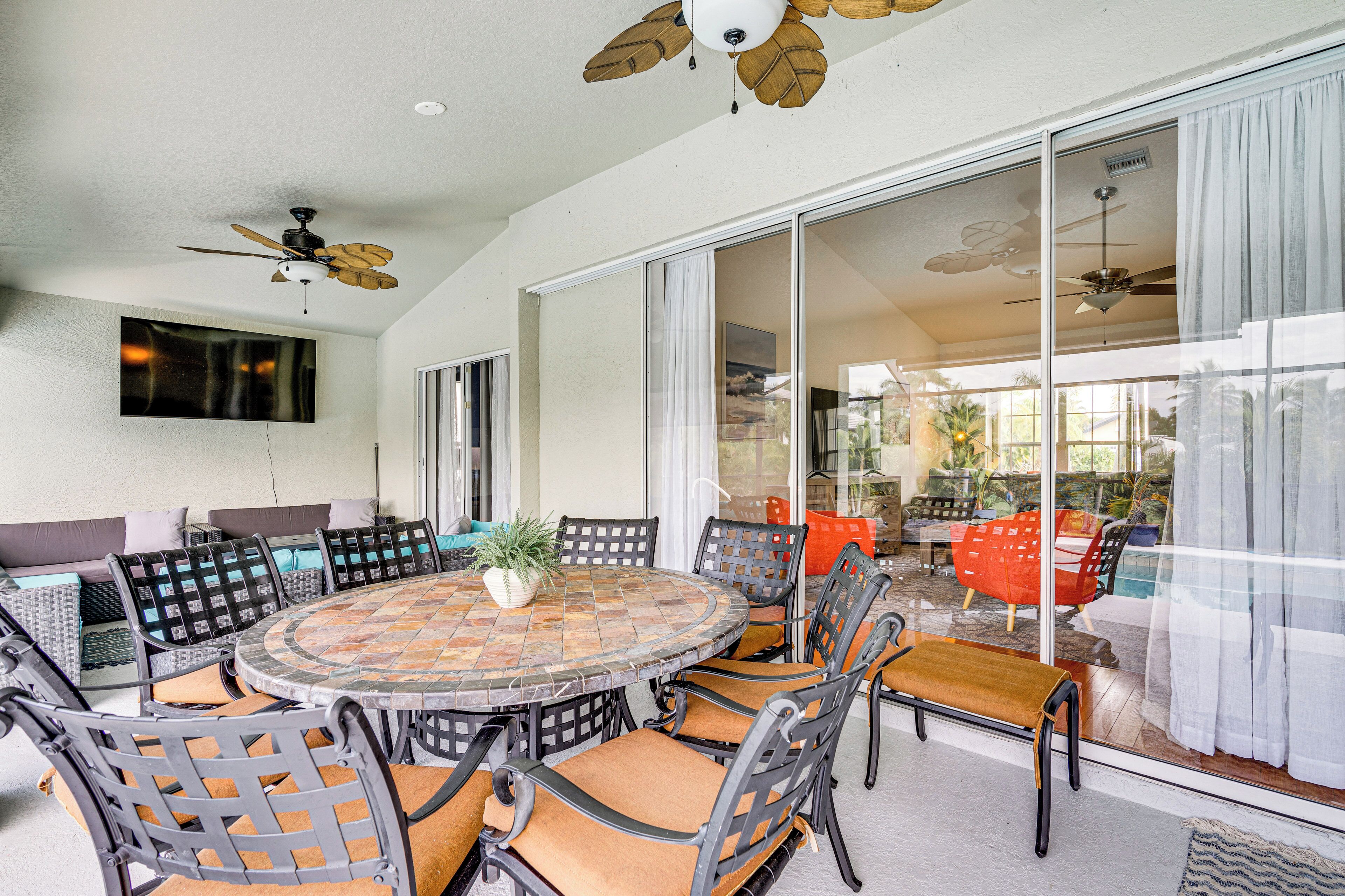 A spacious patio with a round table, chairs, and ceiling fans.