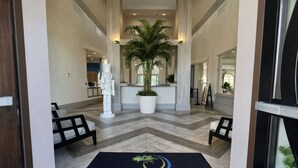 Un hall de hotel con mostrador de recepción, una planta grande en maceta y un mostrador de registro.