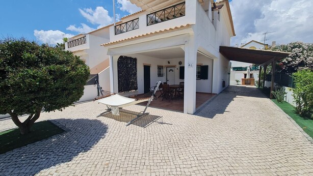 A two-story house with a covered patio area, a dining table, and a hammock. - Belsol House (Altura)