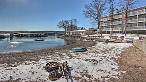 A waterfront property with a dock, a snow-covered beach, and a building with balconies. - Balcony w/ Lake Views: Waterfront Ozarks Condo! (Osage Beach)