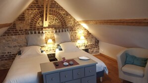 Ein gemütliches Schlafzimmer im Dachgeschoss mit Backsteinwand, zwei Betten, einem Schminktisch und einem Stuhl.