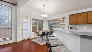 A modern kitchen with a central island, wooden cabinets, and a dining area with a table and chairs.