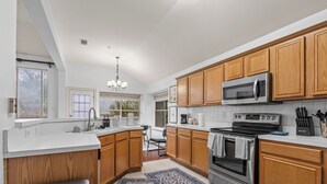 A modern kitchen with wooden cabinets, stainless steel appliances, and a large island.