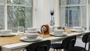A dining table set with white plates, bowls, and glasses, a decorative vase, and a wooden bowl.