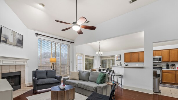 A spacious living room with a fireplace, a ceiling fan, and a view into the dining area.