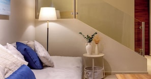 A modern bedroom with a bed, pillows, a bedside table with a vase, and a lamp. - Casa Venado | Private Pool · Peaceful rest · Across from a Park · Parking (Mérida)