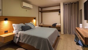 Une chambre d’hôtel bien aménagée, avec un lit, des tables de chevet, un bureau, une chaise, une télévision et un appareil de climatisation.