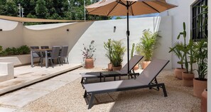 An outdoor patio with a table and chairs, lounge chairs, and potted plants. - Casa Venado | Private Pool · Peaceful rest · Across from a Park · Parking (Mérida)