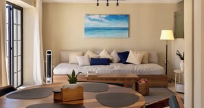 Una sala de estar acogedora con un sofá, un cuadro de una playa, un calentador portátil y un comedor con mesa y sillas.