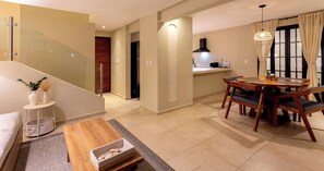 A modern living room with a sofa, a coffee table, and a dining area with a table and chairs. - Casa Venado | Private Pool · Peaceful rest · Across from a Park · Parking (Mérida)