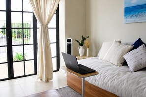 A bedroom with a laptop on a bedside table, a bed with pillows, a nightstand with a vase, and a window with curtains. - Casa Venado | Private Pool · Peaceful rest · Across from a Park · Parking (Mérida)