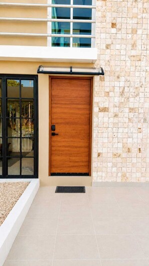 A modern building with a wooden door, a tiled wall, and a window with a view. - Casa Venado | Private Pool · Peaceful rest · Across from a Park · Parking (Mérida)