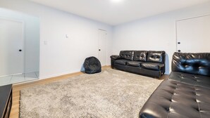 A room with a black leather sofa, a black bean bag chair, and a grey shag rug. - Modern 1BR Apt Near Lake & Downtown (Sandwich)