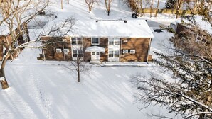 A two-story house with a snow-covered roof and a front porch. - Modern 1BR Apt Near Lake & Downtown (Sandwich)