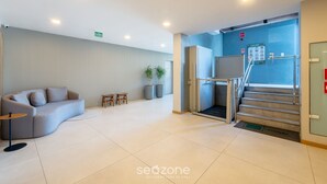 A modern lobby with a curved sofa, a small table, and potted plants. - Fully Equipped Apts With Leisure Minutes From the Beach Hfos (Salvador)