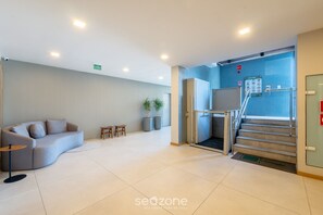A modern lobby with a curved sofa, a small table, and potted plants. - Fully Equipped Apts With Leisure Minutes From the Beach Hfos (Salvador)