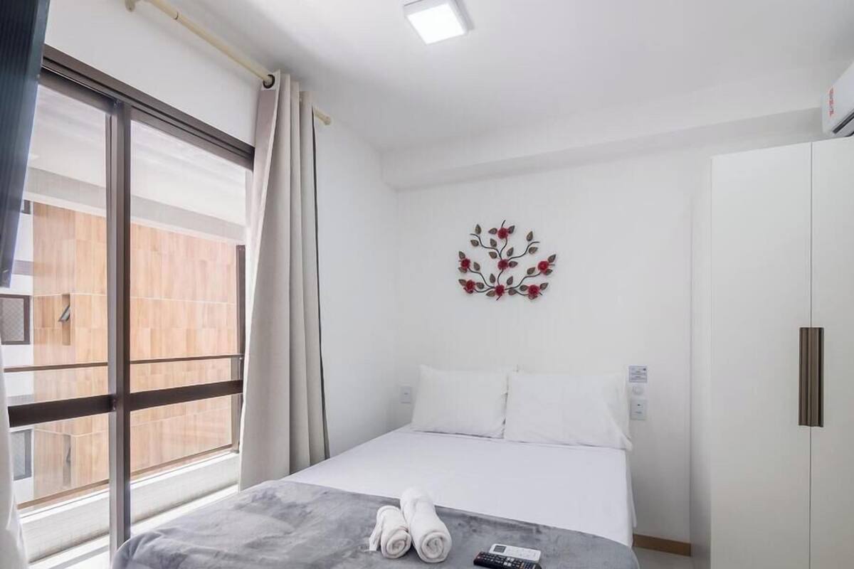 A hotel room with a bed, a wall-mounted decoration, a wardrobe, and a window with curtains.