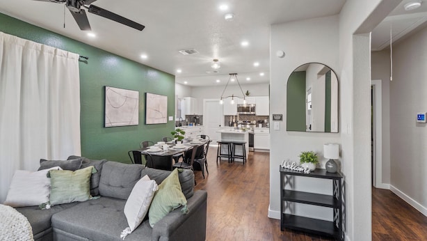 A modern living room with a gray sectional sofa, dining area, kitchen, and a ceiling fan. - Botanical Oasis Near Riverwalk - Sleeps 12 (San Antonio)