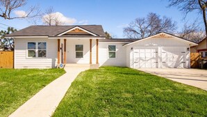 A single-story house with a front porch, a garage, and a well-maintained lawn. - Botanical Oasis Near Riverwalk - Sleeps 12 (San Antonio)