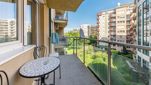 A balcony with a tiled table and chairs, a blue towel, and a view of surrounding apartment buildings. - La Dolce Vita –Massage Shower Stay W/ Ac + Balcony (Budapest)