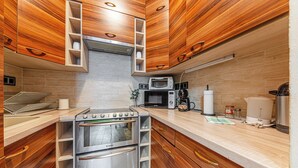 A compact kitchen with a built-in oven, microwave, and coffee maker. - La Dolce Vita –Massage Shower Stay W/ Ac + Balcony (Budapest)