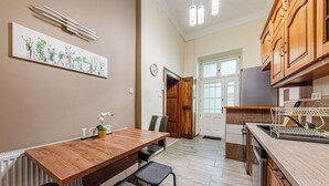 A modern kitchen with wooden cabinets, a dining table with chairs, and a kitchen island with a sink. - Krisztina Residence –Cozy Family Gem By Castle (Budapest)