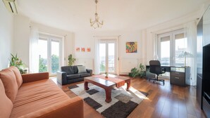 A spacious living room with a sofa, a coffee table, and a desk area. - Aurelia Suite – Spacious W/ Ac & Danube View (Budapest)