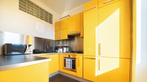 A modern kitchen with yellow cabinets, stainless steel appliances, and a tiled floor. - Aurelia Suite – Spacious W/ Ac & Danube View (Budapest)
