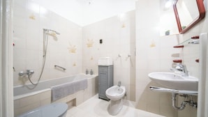 Een badkamer met een bad, toilet, toiletbrons en wastafel.