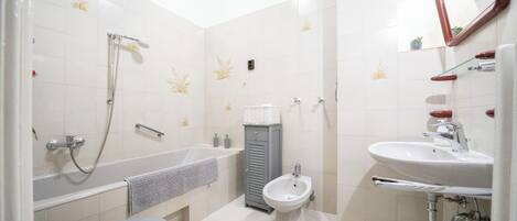 A bathroom with a bathtub, toilet, bidet, and sink.