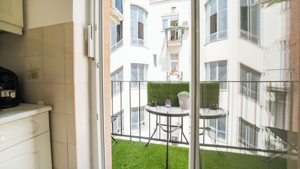 Een balkon met een kleintje tafeltje, stoelen en potplanten.