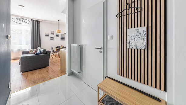 Un salon moderne avec un canapé gris, un parquet en bois et un coin repas à l’arrière-plan.