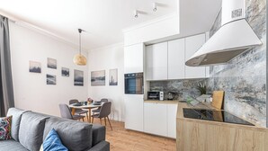 Un appartement moderne comprenant un coin repas, une kitchenette et un salon avec un canapé et des coussins.
