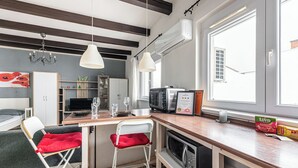 Een kleine keuken met een houten aanrecht, een broodrooster, een magnetron en een raam met jaloezieën.