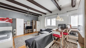 Een moderne woonkamer met een bank, tv en een eethoek.