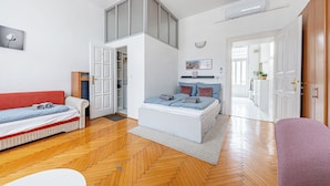 Une chambre moderne comprenant un lit, un canapé, une armoire et un couloir menant à une autre pièce.