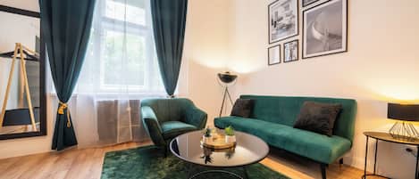 A modern living room with a green sofa, a round coffee table, and a green rug.