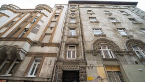 Ein mehrstöckiges Gebäude mit klassischer Architektur, darunter Säulen, Rundbogenfenster und dekorative Verzierungen.