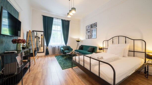 Ein modernes Hotelzimmer mit Bett, Sofa, Fernseher und Schreibtisch.