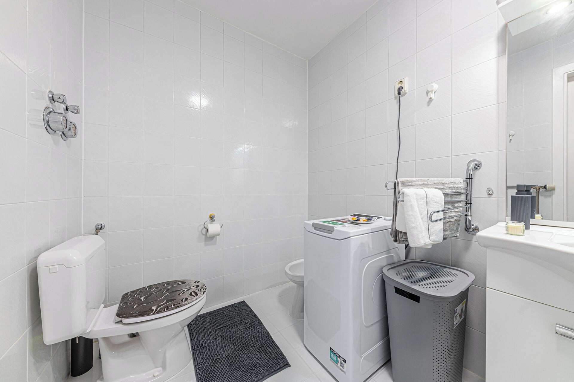 A modern bathroom with a toilet, bidet, and a trash bin.