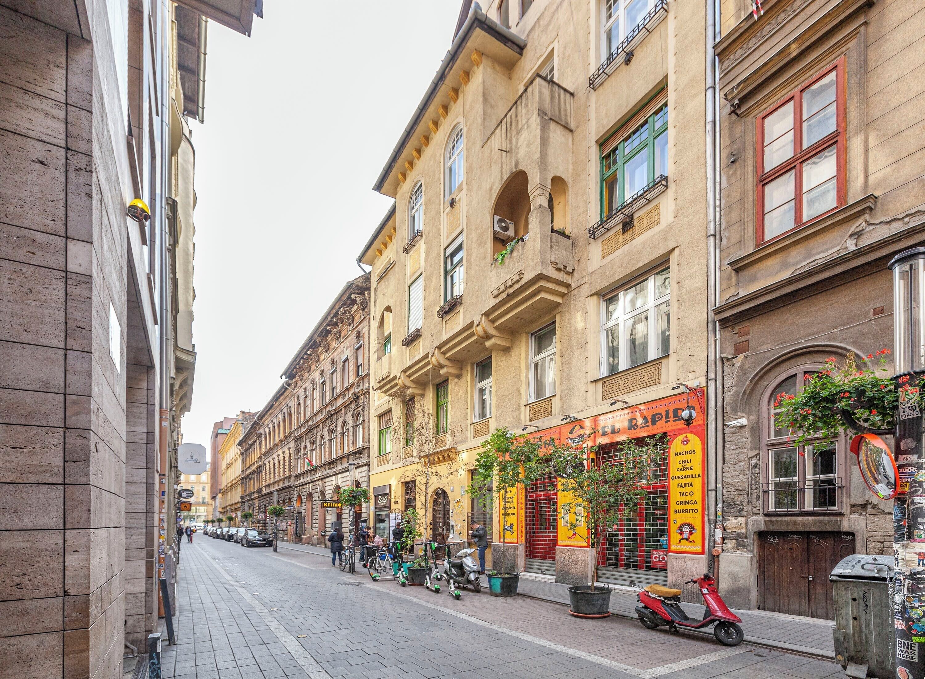 Une rue bordée de bâtiments historiques, un restaurant appelé « El Rapito » et un scooter garé sur le trottoir.