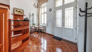 Een ruime hal met een houten receptiebalie, een kroonluchter, een zithoek met stoelen en een grote deur met een metalen hekwerk.