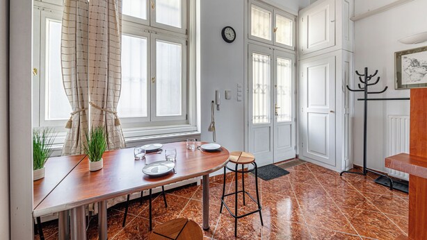 Een keuken met een eettafel, stoelen, een klok en een kapstok.