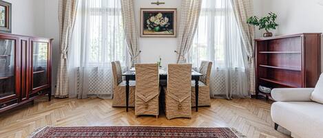 A dining area with a table, chairs, a painting, and a bookshelf.